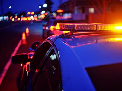 Police car with flashing red and blue lights at a nighttime traffic stop in Texas.