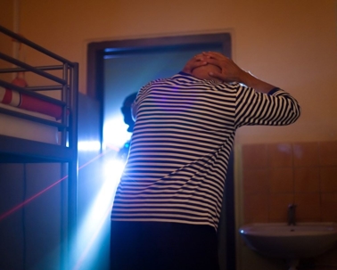 man in a striped shirt holding his hands behind his head